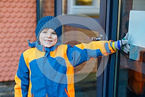 Little school kid boy of elementary class walking to school on cold winter day. Happy child in warm winter clothes