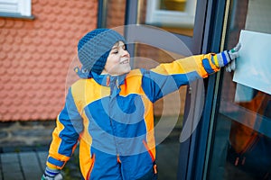 Little school kid boy of elementary class walking to school on cold winter day. Happy child in warm winter clothes