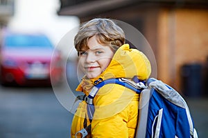 Little school kid boy of elementary class walking to school. Portrait of happy child on the street with traffic. Student