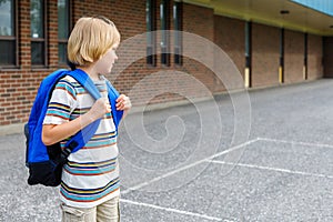 Little schoolboy going to school, carrying backpack. Back to school concept photo