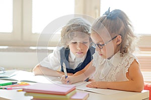 Little schoolboy and schoolgirl diligently doing their homework.