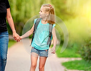 Little schooler walking with mother in park