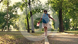 A little schoolgirl with a backpack and a book goes home through the Park. Rear view. A child hurries to the Playground