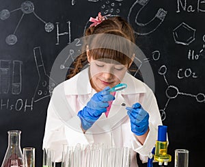 Little schoolgirl looking through magnifier on reagents