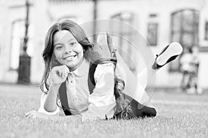 Little schoolgirl. Relax at school yard. Nice time. School break for rest. Adorable pupil. Girl kid laying green grass