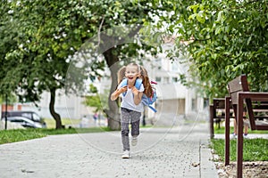 The little schoolgirl is running with a backpack and laughing. The concept of school, study, education, friendship, childhood