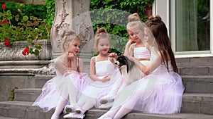 Little schoolgirls of ballet school sit on a porch of school