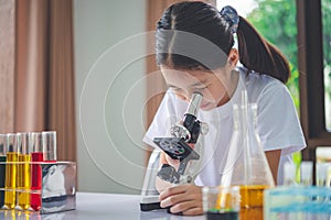 little scientist looking through a microscope and test tubes filled with chemicals for learning about science and experiments