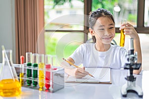 little scientist looking through a microscope and test tubes filled with chemicals for learning about science and experiments
