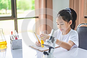 little scientist looking through a microscope and test tubes filled with chemicals for learning about science and experiments