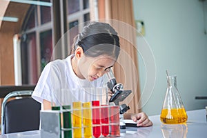 little scientist looking through a microscope and test tubes filled with chemicals for learning about science and experiments