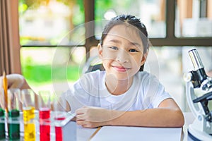 little scientist looking through a microscope and test tubes filled with chemicals for learning about science and experiments