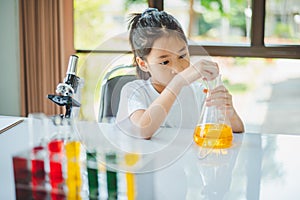 little scientist looking through a microscope and test tubes filled with chemicals for learning about science and experiments