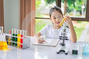 little scientist looking through a microscope and test tubes filled with chemicals for learning about science and experiments