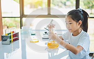 little scientist looking through a microscope and test tubes filled with chemicals for learning about science and experiments