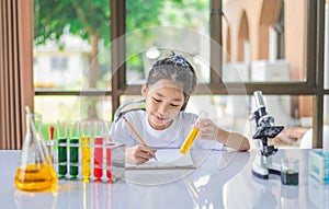 little scientist looking through a microscope and test tubes filled with chemicals for learning about science and experiments