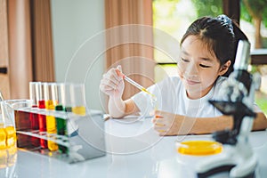 little scientist looking through a microscope and test tubes filled with chemicals for learning about science and experiments