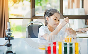 little scientist looking through a microscope and test tubes filled with chemicals for learning about science