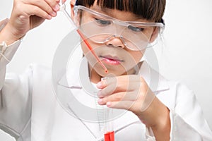 Little scientist. Smiling little girl learning classroom in school lab holding test tubes. Little girl playing science experiment
