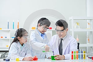 Little scientists adding color dye into beakers