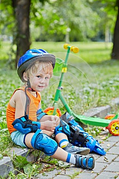 Little scooterist in protective equipment rests