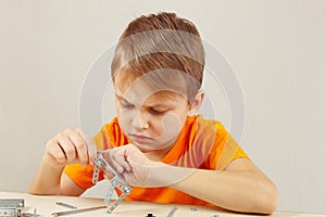 Little serious boy plays with mechanical starter kit at table