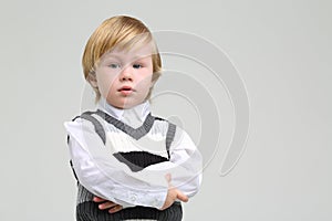 Little serious boy in vest and shirt looks away on