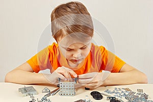 Little serious engineer plays with mechanical starter kit at table