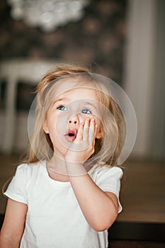 Little shaggy blonde baby girl with blue eyes is smiling after her morning awaking