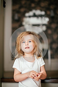 Little shaggy blonde baby girl with blue eyes is smiling after her morning awaking