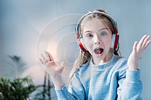 Little shocked girl listening music in headphones