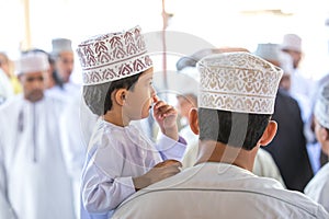 Little shy boy leaning against the shoulder of his father.