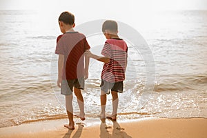 Little sibling boy jumping over the beach