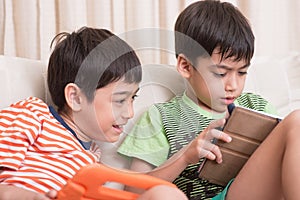 Little sibling boy playing game on mobile tablet with happy together