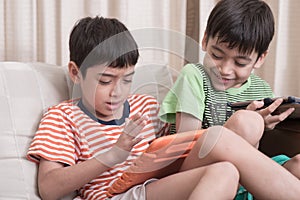 Little sibling boy playing game on mobile together at home