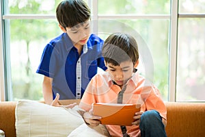 Little sibling boy playing game on mobile together house living room