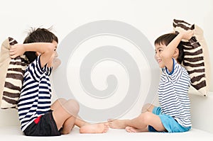 Little sibling boy playing pillow fighting on sofa