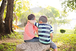 Little sibling boy sitting together in the park outdoor