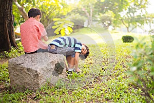 Little sibling boy sitting together in the park outdoor