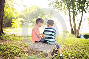 Little sibling boy sitting together in the park outdoor