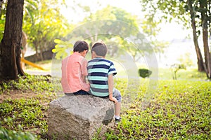 Little sibling boy sitting together in the park outdoor