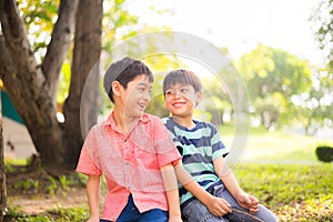 Little sibling boy sitting together in the park outdoor