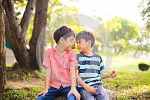 Little sibling boy sitting together in the park outdoor