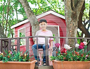 Little sibling boy sitting in the tree house eating ice cream