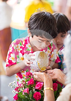 Little sibling boy taking a bowl for playing water in water festival