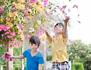 Little sibling boy throw flowers in to the air