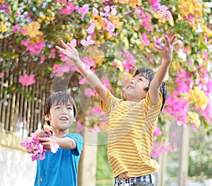 Little sibling boy throw flowers in to the air with smiling