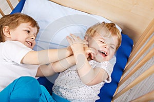 Little sibling boys having fun in bed at home