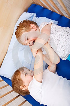Little sibling boys having fun in bed at home