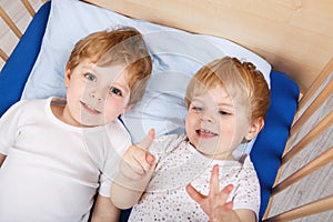 Little sibling boys having fun in bed at home